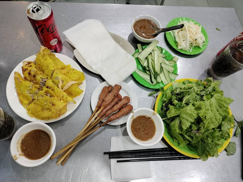 Bánh xèo, nem lụi, rau xanh và nước chấm trên bàn inox